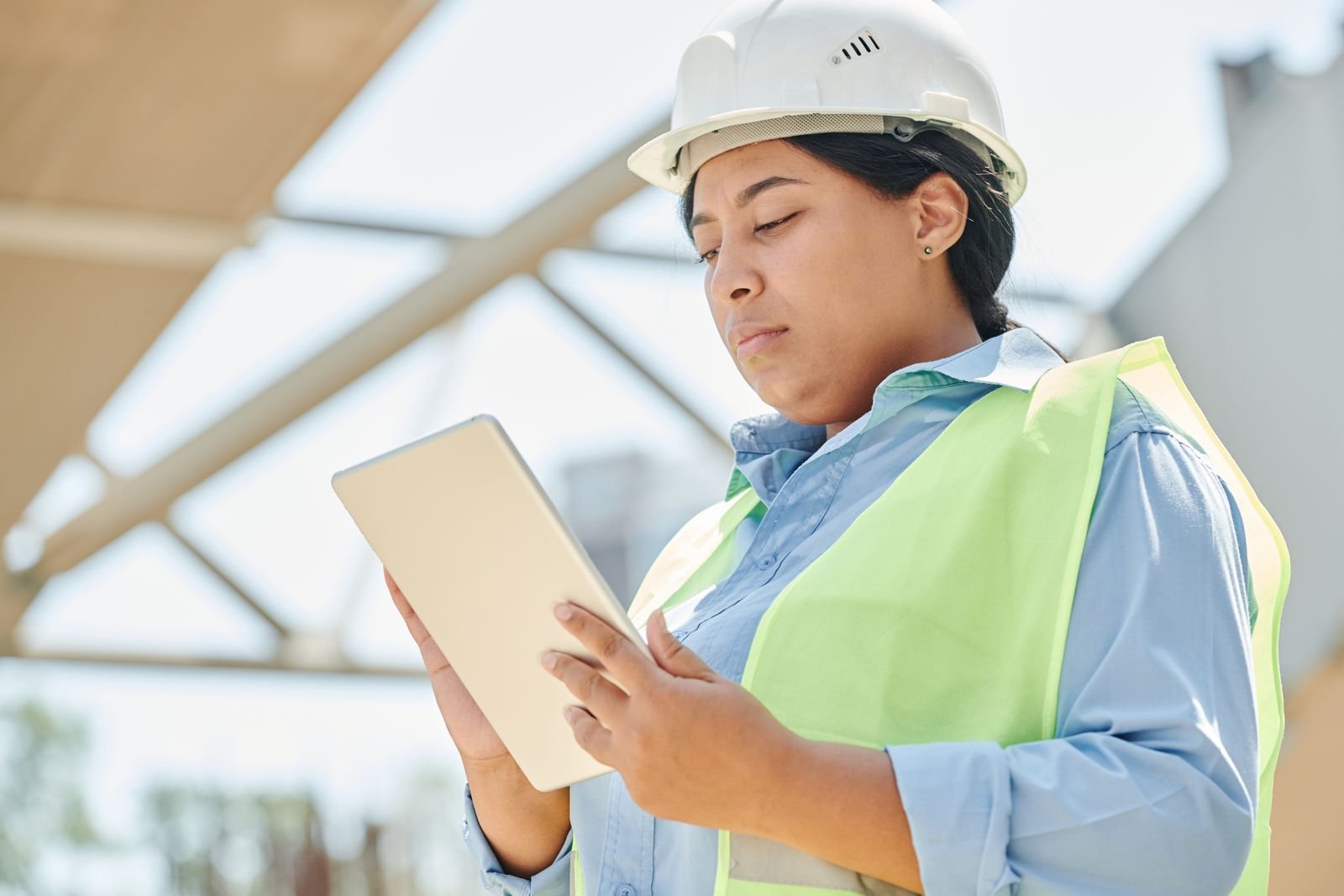 Engineer in a hard hat using a tablet computer on site.