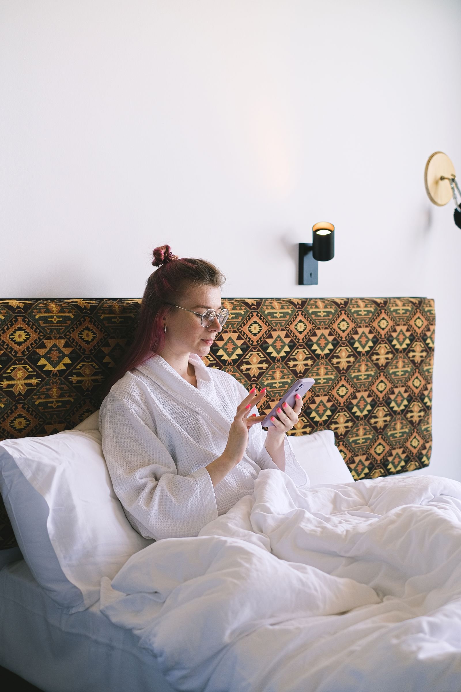Hotel guest using a smartphone booking app in a room.