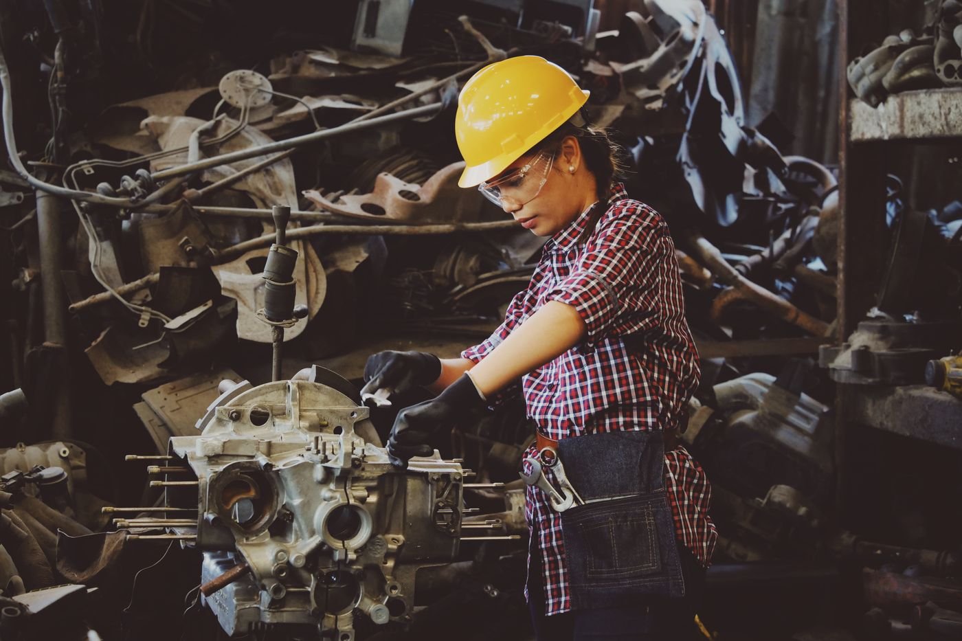 Factory worker in hard hat and safety glasses working on production equipment.