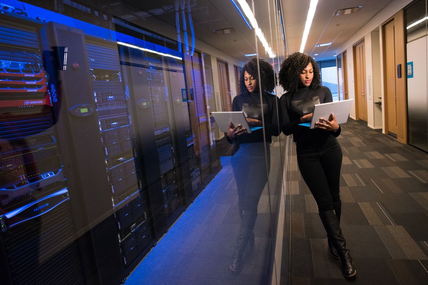 Engineer in a server room with a laptop, monitoring automated systems.