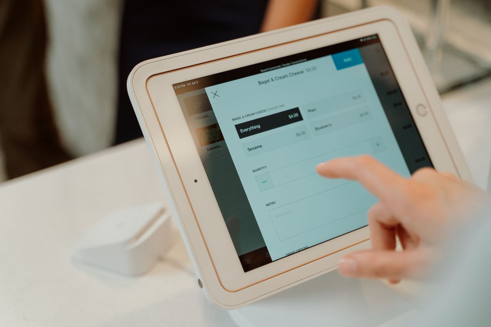 A retail POS touchscreen terminal in use, taking an order.
